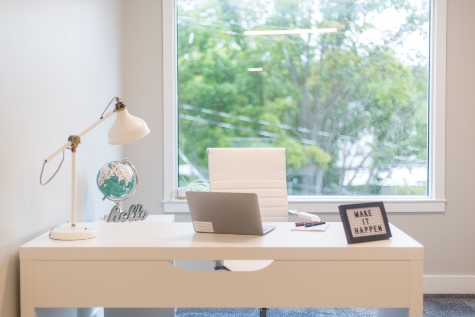 Cream desk in front of a window with trees outside